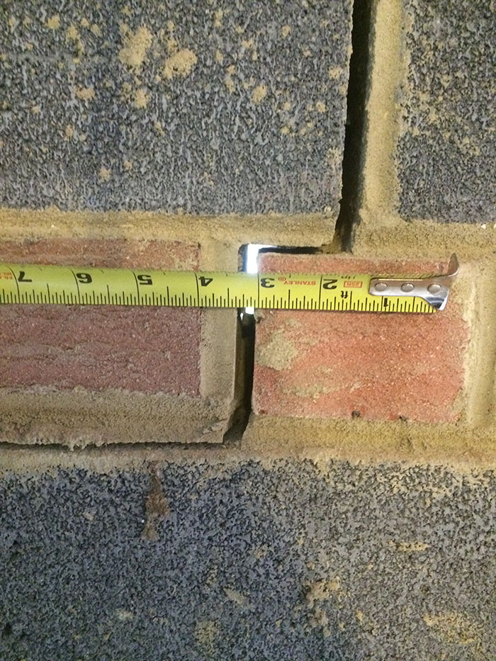 Tape measurement documenting a gap in a masonry basement wall during assessment